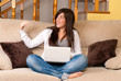 Photo: Young woman with laptop portable computer sitting on sofa Young woman with laptop portable computer sitting on sofa