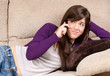 Photo: Young girl concerned talking by telephone bad news lying on sofa Young girl concerned talking by telephone bad news lying on sofa