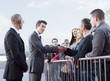 Politician shaking hands with people behind barrier