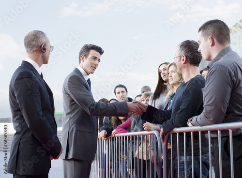 Photo: Politician shaking hands with people behind barrier Politician shaking hands with people behind barrier