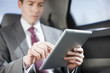 Businessman using tablet computer in backseat of car