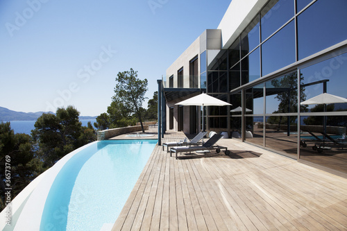Foto: Lounge chairs and pool outside modern house Lounge chairs and pool outside modern house