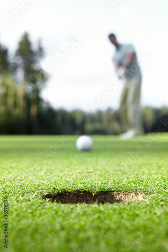 Photo: A man scores ball in the hole A man scores ball in the hole