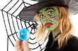 green Halloween witch girl in closeup holding big blue marble