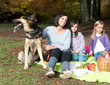 Mother with two daughters and a dog on picnic in forest