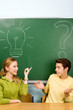Two students with light bulb and question mark on chalkboard