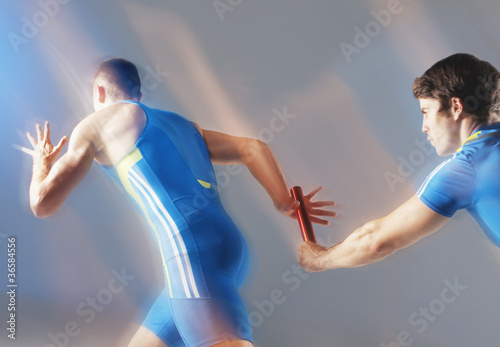 Photo: Blurred view of athletes passing baton Blurred view of athletes passing baton