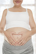 Pregnant woman making heart around navel