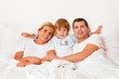 Familie liegt am Morgen im Bett