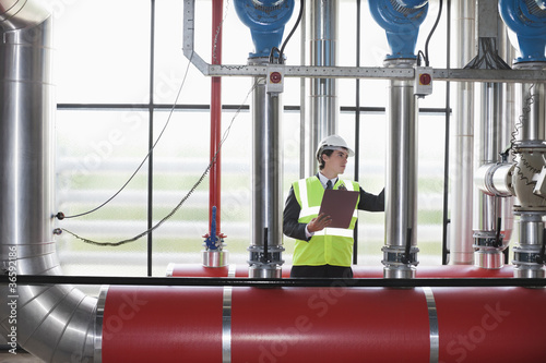 Photo: Businessman checking pipes in factory Businessman checking pipes in factory