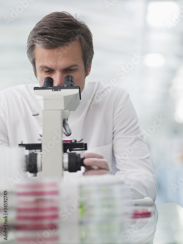 Photo: Scientist using microscope in lab Scientist using microscope in lab
