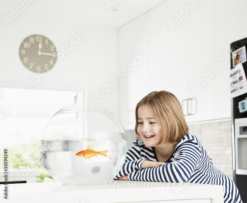 Foto: Girl examining goldfish in bowl Girl examining goldfish in bowl