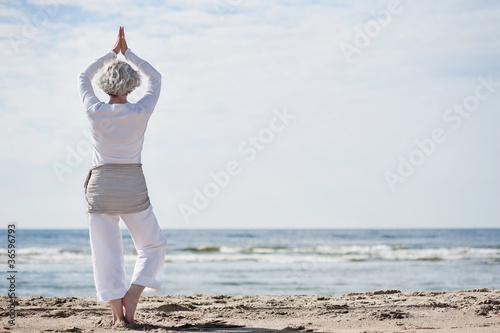 Photo: aktive Seniorin macht Yoga am Strand aktive Seniorin macht Yoga am Strand