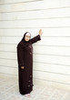 Muslim woman beside white wall