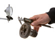 Measuring gearwheel with calipers with dial gauge in background.
