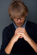 Young man praying against grey background