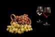 Foto: Cesto con uva e calici di vino su sfondo nero Cesto con uva e calici di vino su sfondo nero
