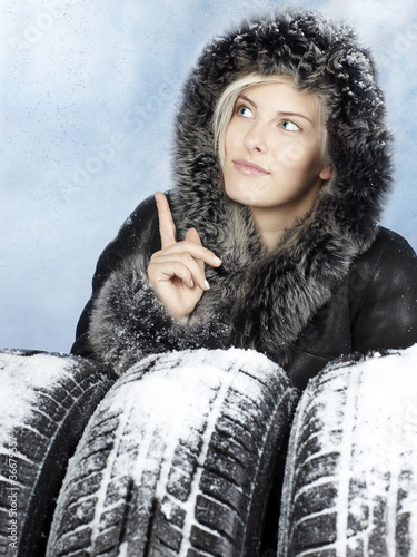 Photo: Beautiful woman with winter coat with snowy winter tyres Beautiful woman with winter coat with snowy winter tyres