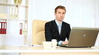 Businessman working in office looking at camera.