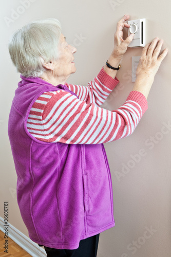 Photo: Senior woman adjusting her thermostat Senior woman adjusting her thermostat