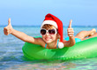 Child in santa hat  floating on inflatable ring in sea.