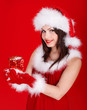 Girl in Santa hat holding gift box on red background.