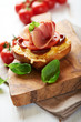 Crostini with prosciutto crudo and chorizo on wooden board