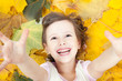 Cute little smiling girl in autumn leaves