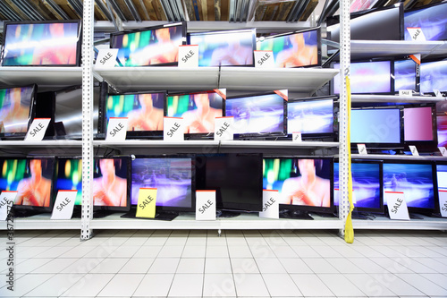 Photo: Plasma TVs with big diagonal stand on shelves in large shop Plasma TVs with big diagonal stand on shelves in large shop