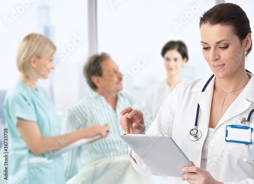 Photo: Doctor making notes at patients bed Doctor making notes at patients bed