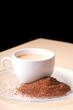 Cup of coffee on clear plate with grounds