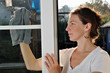 Junge Frau putzt Fenster