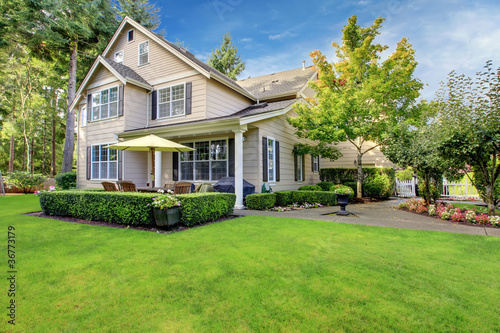 Photo: Large beige house with green grass Large beige house with green grass