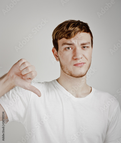 Photo: young man shows thumb down young man shows thumb down