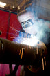 factory worker welding metal and sparks spreading