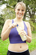 Junge Frau beim Joggen trinkt