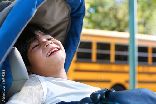 Photo: Disabled five year old boy in wheelchair outdoors by school bus Disabled five year old boy in wheelchair outdoors by school bus