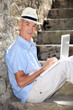 elderly gentleman working outdoors on laptop