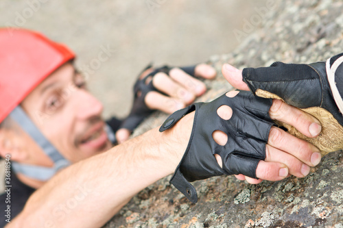 Photo: The help two rock-climbers each other in outdoor The help two rock-climbers each other in outdoor