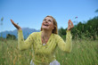 Pretty healthy summer woman outdoors on green field in Alps enjo