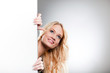 Foto: Woman hiding behind a white wall Woman hiding behind a white wall