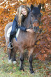 Young girl on horseback stroking a horse