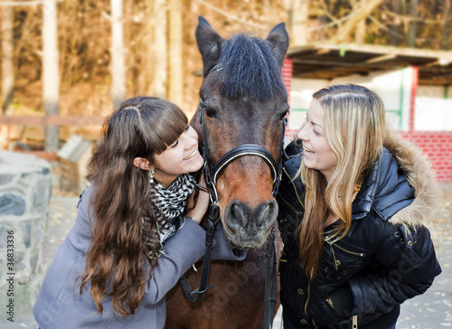 Foto: Two girls holding a horse Two girls holding a horse