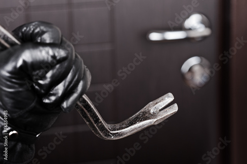 Photo: Burglar hand holding crowbar break opening door Burglar hand holding crowbar break opening door