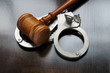Gavel and handcuffs on wooden background