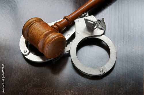 Photo: Gavel and handcuffs on wooden background Gavel and handcuffs on wooden background