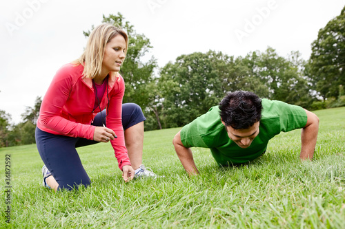 Photo: Trainer coaching man doing push ups Trainer coaching man doing push ups