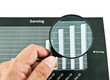 Hand holding magnifying glass over diagram.