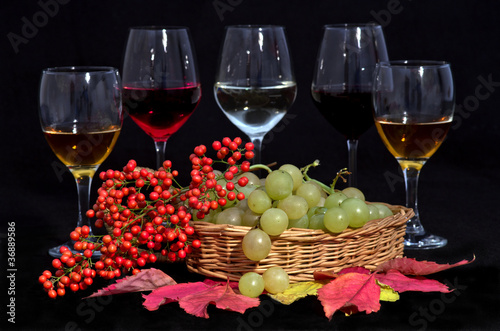 Foto: Uva bianca, bacche rosse e calici di vino su fondo nero Uva bianca, bacche rosse e calici di vino su fondo nero