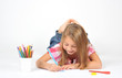 Little girl lying on floor and drawing, isolated on white
